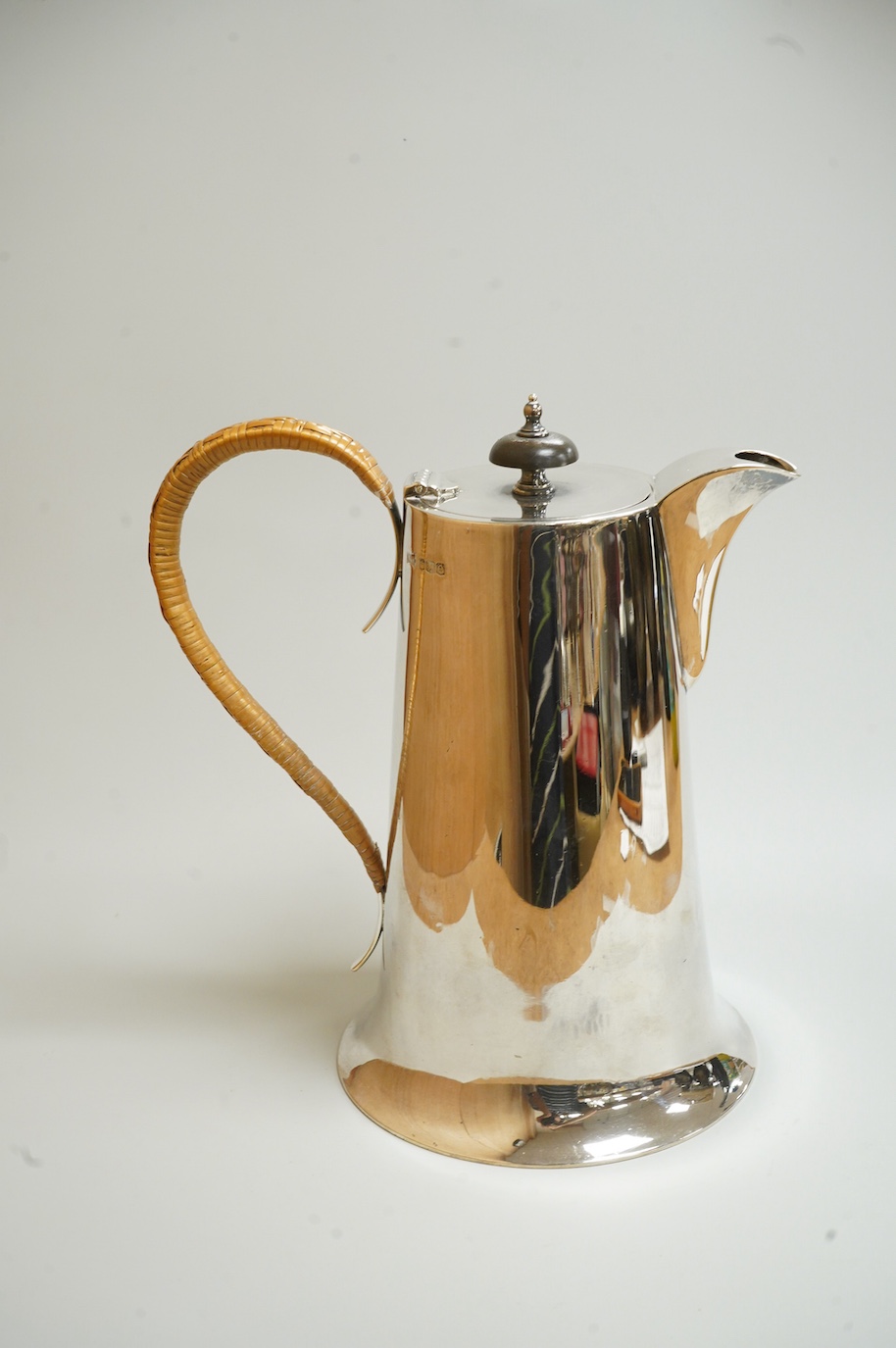 A George V silver hot water jug, by Walker & Hall, Sheffield, 1922, of tapering form, with rattan handle and circular spreading foot, height 22cm, 24.7oz.